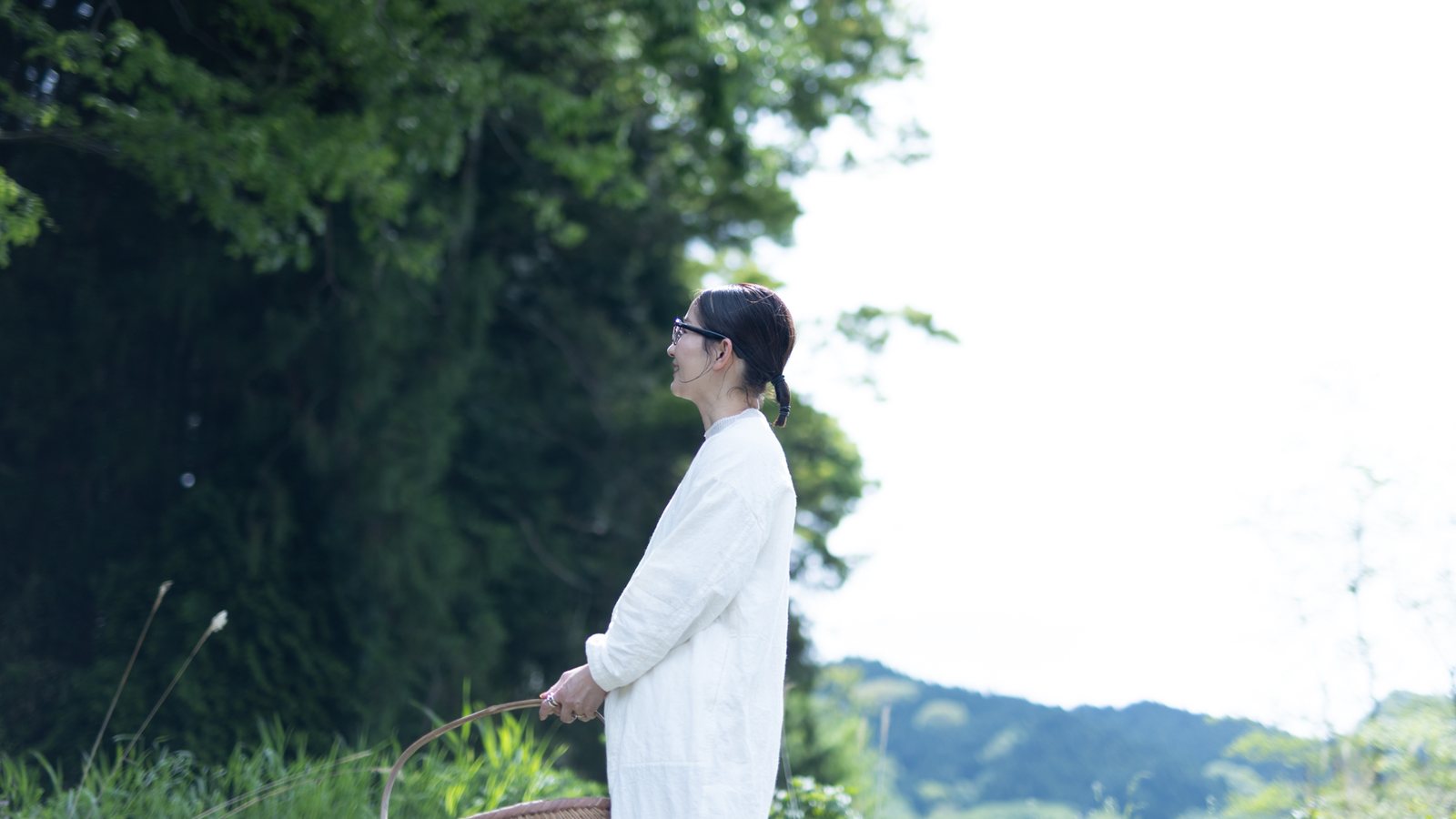 かごを手に、南阿蘇の景色を眺める菊池友来
